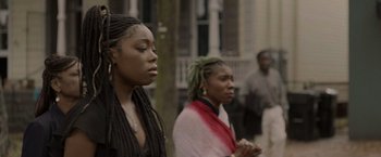 Movie still from “Black as Night” (2021), directed by Maritte Lee Go – Two women standing next to each other on the street; Close Up shot, Over the shoulder angle