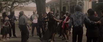 Movie still from “Black as Night” (2021), directed by Maritte Lee Go – A group of people standing next to a tree; Extreme Wide shot, Low angle