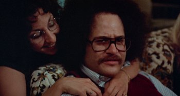 Movie still from “Black Christmas” (1974), directed by Bob Clark – A woman is holding a man's shoulder and smiling; Close Up shot, High angle