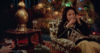 Movie still from “Black Christmas” (1974), directed by Bob Clark – A woman sitting at a table talking on a phone; Medium shot, High angle