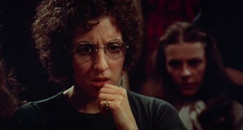 Movie still from “Black Christmas” (1974), directed by Bob Clark – A woman with glasses is sitting in front of another woman; Close Up shot, Over the shoulder angle