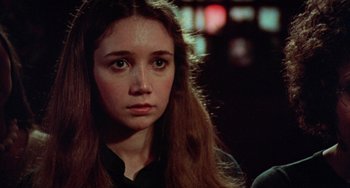 Movie still from “Black Christmas” (1974), directed by Bob Clark – A young woman with long brown hair looking at the camera; Close Up shot, Over the shoulder angle