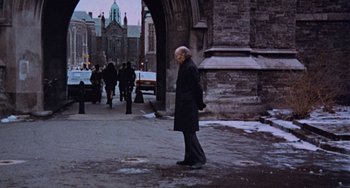 Movie still from “Black Christmas” (1974), directed by Bob Clark – An old man walking down the street in a black coat; Wide shot, High angle