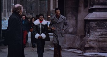 Movie still from “Black Christmas” (1974), directed by Bob Clark – A man and a woman walking down a street; Wide shot, Low angle