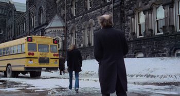 Movie still from “Black Christmas” (1974), directed by Bob Clark – Two people walking on the sidewalk in front of a building; Wide shot, Low angle