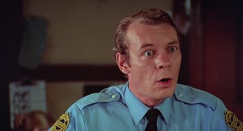 Movie still from “Black Christmas” (1974), directed by Bob Clark – A person wearing a police uniform; Close Up shot, Over the shoulder angle