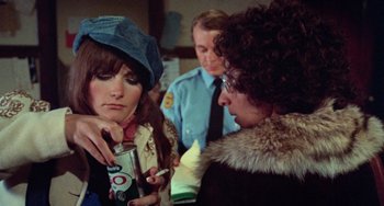 Movie still from “Black Christmas” (1974), directed by Bob Clark – A woman is holding a can of soda while another woman is talking to a man; Close Up shot, Over the shoulder angle