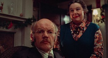 Movie still from “Black Christmas” (1974), directed by Bob Clark – An older man and a younger woman are posing for a picture; Close Up shot, Over the shoulder angle