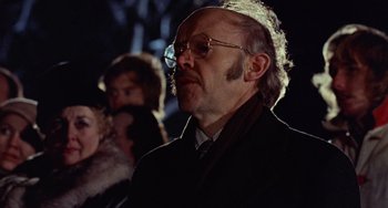 Movie still from “Black Christmas” (1974), directed by Bob Clark – An older man wearing glasses and a black coat; Close Up shot, Over the shoulder angle