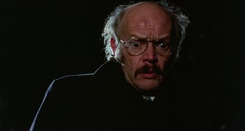 Movie still from “Black Christmas” (1974), directed by Bob Clark – An old man with a beard and glasses is looking at the camera; Close Up shot, Low angle