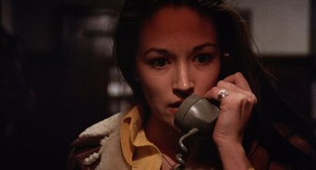 Movie still from “Black Christmas” (1974), directed by Bob Clark – A woman is talking on a phone while holding it to her ear; Close Up shot, Low angle