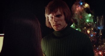 Movie still from “Black Christmas” (1974), directed by Bob Clark – A man in a green sweater looking at the camera; Close Up shot, Over the shoulder angle