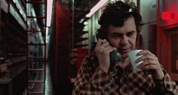 Movie still from “Black Christmas” (1974), directed by Bob Clark – A man talking on a phone while holding a coffee cup; Close Up shot, Low angle