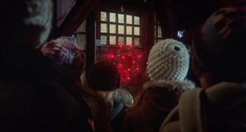Movie still from “Black Christmas” (1974), directed by Bob Clark – A group of people wearing knitted hats looking at a christmas tree; Wide shot, Low angle