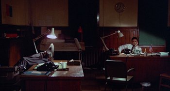 Movie still from “Black Christmas” (1974), directed by Bob Clark – A person sitting at a desk in a dark room; Wide shot, High angle