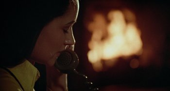 Movie still from “Black Christmas” (1974), directed by Bob Clark – A woman is talking on a phone in front of a fire place; Close Up shot, High angle