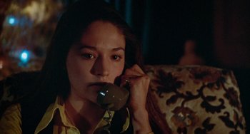 Movie still from “Black Christmas” (1974), directed by Bob Clark – A woman is talking on a phone while sitting on a couch; Close Up shot, High angle
