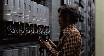 Movie still from “Black Christmas” (1974), directed by Bob Clark – A man holding a pair of wrenches in front of a row of beer taps; Medium shot, Low angle