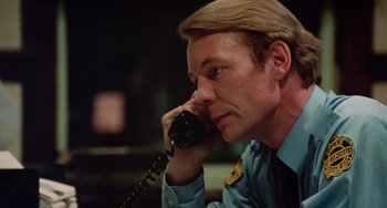 Movie still from “Black Christmas” (1974), directed by Bob Clark – A man talking on a phone while sitting down; Close Up shot, Low angle