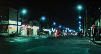 Movie still from “Black Christmas” (1974), directed by Bob Clark – A city street at night lit up by streetlights; Extreme Wide shot, Low angle