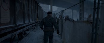 Movie still from “Black Crab” (2022), directed by Adam Berg – A man in a military uniform walking through a snow covered street; Wide shot, Over the shoulder angle