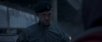 Movie still from “Black Crab” (2022), directed by Adam Berg – A man in a military uniform wearing a hat; Close Up shot, Low angle