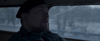 Movie still from “Black Crab” (2022), directed by Adam Berg – A man sitting in the passenger seat of a car in the rain; Close Up shot, Over the shoulder angle