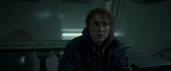 Movie still from “Black Crab” (2022), directed by Adam Berg – A woman with curly red hair wearing a black jacket; Close Up shot, Over the shoulder angle