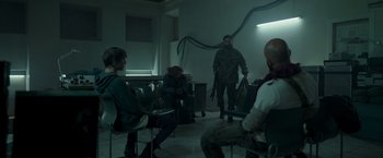 Movie still from “Black Crab” (2022), directed by Adam Berg – A group of people sitting around in a room; Wide shot, Over the shoulder angle