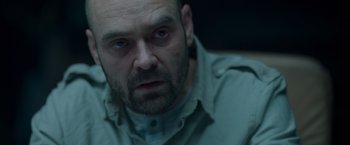 Movie still from “Black Crab” (2022), directed by Adam Berg – A person wearing a shirt; Close Up shot, High angle