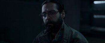 Movie still from “Black Crab” (2022), directed by Adam Berg – A man with a beard wearing glasses looking at the camera; Close Up shot, Low angle