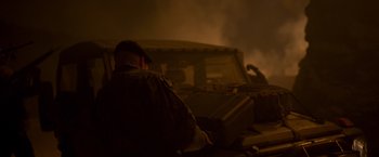 Movie still from “Black Crab” (2022), directed by Adam Berg – A man sitting on the hood of a truck at night; Medium shot, Low angle