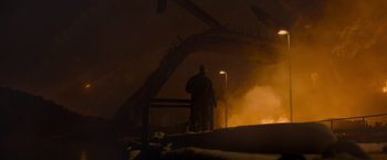 Movie still from “Black Crab” (2022), directed by Adam Berg – A man standing in front of an overpass at night; Extreme Wide shot, Low angle
