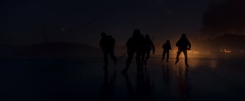 Movie still from “Black Crab” (2022), directed by Adam Berg – A group of people walking across a lake at night; Extreme Wide shot, Low angle