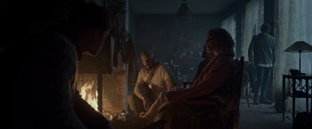 Movie still from “Black Crab” (2022), directed by Adam Berg – A man and a woman sitting in front of a fire; Wide shot, Over the shoulder angle