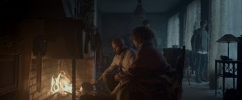 Movie still from “Black Crab” (2022), directed by Adam Berg – A man and a woman sitting in front of an open fire; Wide shot, Low angle