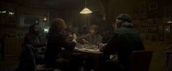 Movie still from “Black Crab” (2022), directed by Adam Berg – A group of people sitting around a table; Wide shot, Over the shoulder angle