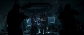 Movie still from “Black Crab” (2022), directed by Adam Berg – Two people standing in a room holding a cell phone; Wide shot, Low angle