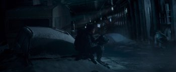 Movie still from “Black Crab” (2022), directed by Adam Berg – A man sitting on the side of a snow covered slope; Wide shot, High angle
