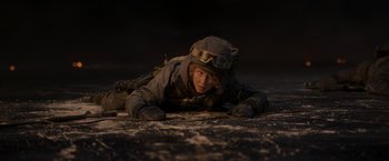 Movie still from “Black Crab” (2022), directed by Adam Berg – A soldier laying on the ground in the dark; Medium shot, High angle