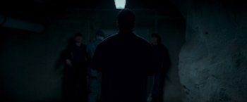 Movie still from “Black Crab” (2022), directed by Adam Berg – A group of men standing in a dark room; Medium shot, Low angle