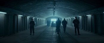 Movie still from “Black Crab” (2022), directed by Adam Berg – A group of people walking down a tunnel; Extreme Wide shot, High angle