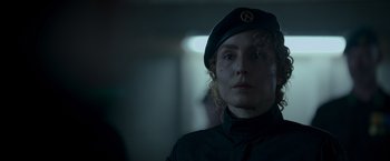 Movie still from “Black Crab” (2022), directed by Adam Berg – A woman wearing a black uniform and a black hat; Close Up shot, Over the shoulder angle
