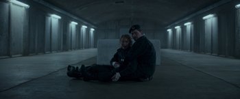 Movie still from “Black Crab” (2022), directed by Adam Berg – A man and a woman sitting on the ground; Medium shot, High angle