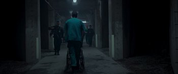 Movie still from “Black Crab” (2022), directed by Adam Berg – A man in a wheelchair is walking down a hallway; Wide shot, High angle