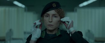 Movie still from “Black Crab” (2022), directed by Adam Berg – A woman in a military uniform holding two bananas in front of her face; Close Up shot, Low angle