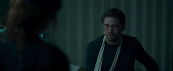 Movie still from “Black Crab” (2022), directed by Adam Berg – A man with a scarf around his neck looks at the camera; Medium shot, Over the shoulder angle