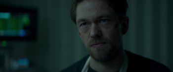 Movie still from “Black Crab” (2022), directed by Adam Berg – A person wearing a black shirt; Close Up shot, Over the shoulder angle