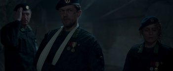 Movie still from “Black Crab” (2022), directed by Adam Berg – A man in a military uniform wearing medals; Medium shot, Over the shoulder angle