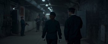 Movie still from “Black Crab” (2022), directed by Adam Berg – A group of people walking down a dark hallway; Medium shot, Over the shoulder angle
